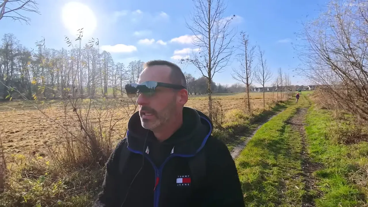 Person trägt RayNeo Air‑Brille auf einem Feldweg bei hellem Sonnenschein, Brille reflektiert Landschaft