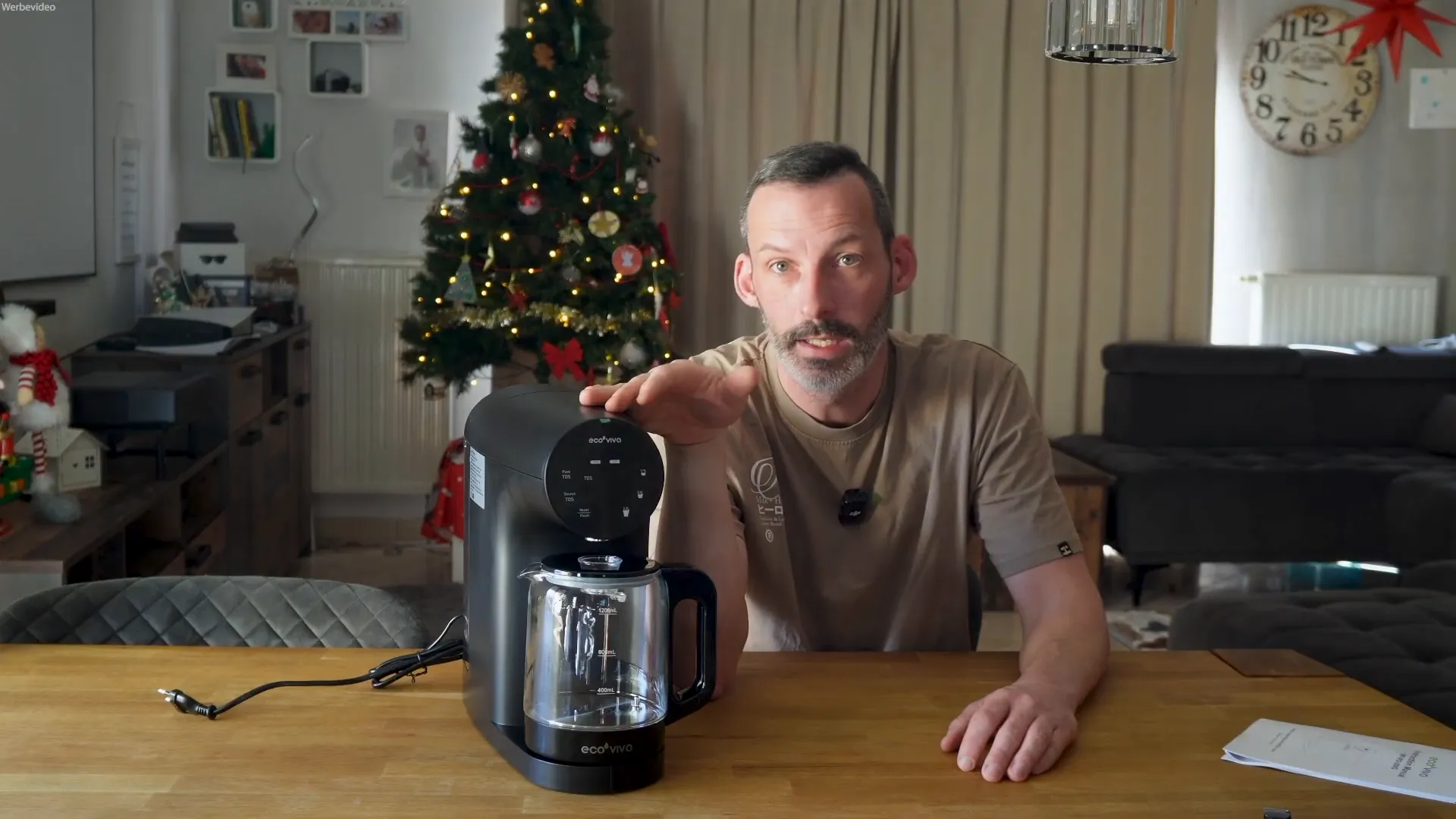 Moderator demonstriert EcoViva Auftisch-Umkehrosmosegerät mit Hand auf Gerät, scharfe Aufnahme