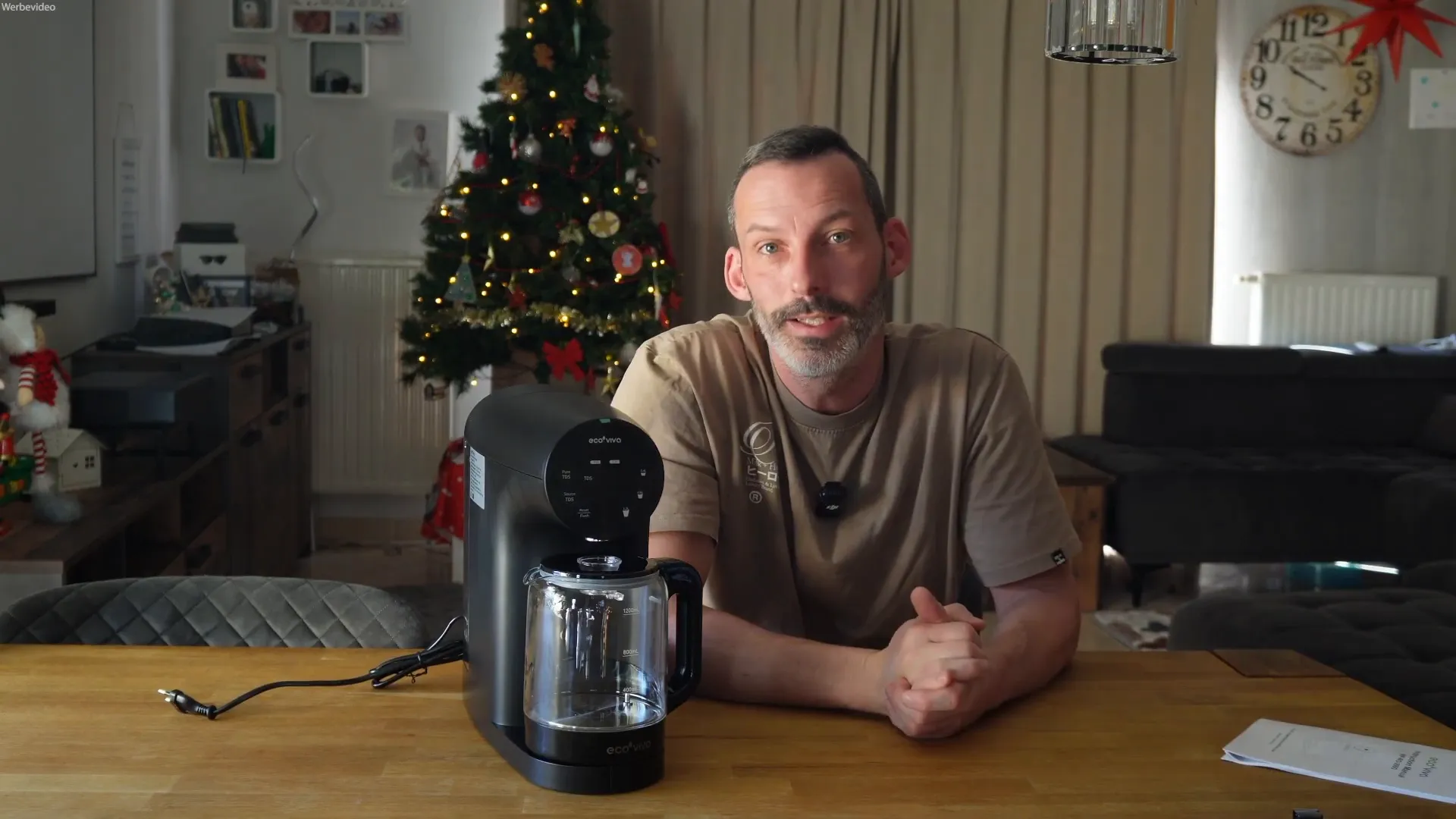 Moderator erklärt Remineralisierung neben EcoViva Umkehrosmosegerät auf Holztisch